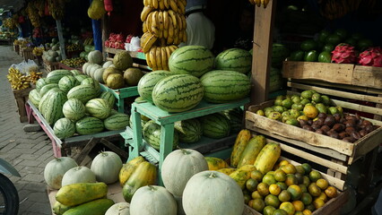 stalls selling fruit in traditional markets. there are bananas, watermelons, dragon fruit, oranges and apples for sale