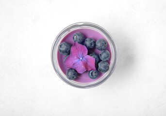 Obraz na płótnie Canvas Glass jar of panna cotta with blueberry and beautiful hydrangea flower on white background