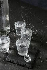 Shots of vodka with ice cubes on black background