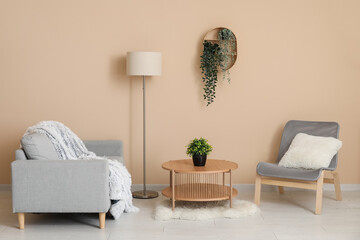 Armchairs with coffee table, lamp and houseplants near beige wall