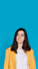 Fototapeta premium Serene Young Woman Contemplating, Gazing into Empty Space, Thoughtful Young Woman in Captivating Portrait, Lost in Contemplation, Isolated on Blue Background.