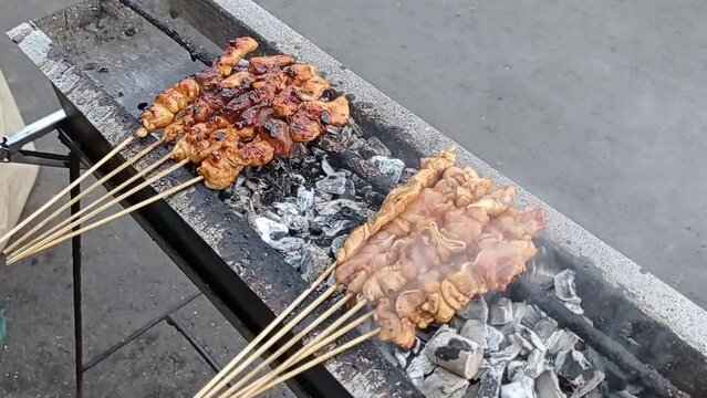 Indonesian chicken satay being grilled over hot charcoal