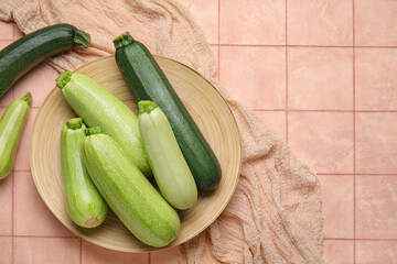 Plate with fresh zucchini on beige tile background