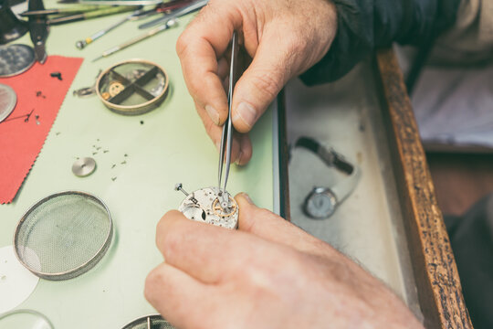 Hands of experienced watchmaker fixing a watch in close-up