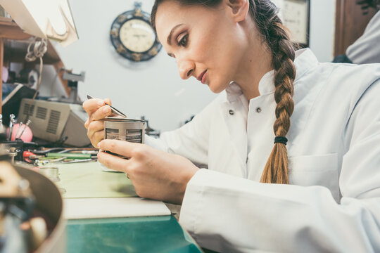 Diligent woman watchmaker working diligently on repairing a watch