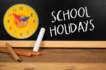 Black school chalk board showing the word school holidays