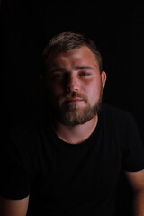 Thoughtful young bearded man on black background