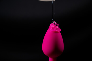 Pink anal plug in intimate lubricant on a black background. Copy space. 