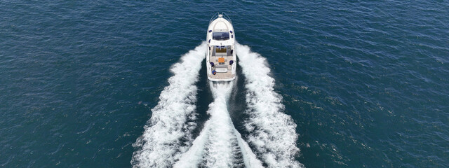 Aerial drone photo of beautiful yacht with wooden deck cruising in high speed deep blue Aegean sea...
