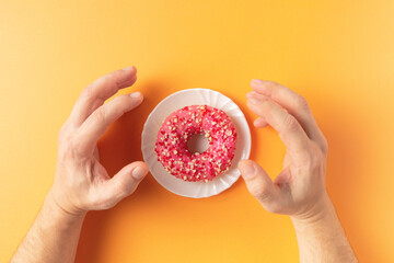 A person really wants to eat a donut. Diet, weight loss, willpower. Blue background.
