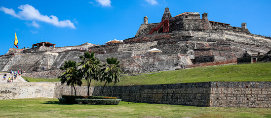 Panorama of Castle San Felipe de Barajas with palm trees in foreground on a sunny day, Cartagena, Colombia