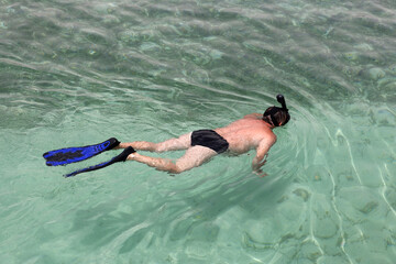 Man in scuba mask swimming in transparent sea water. Snorkeling and diving, beach vacation in summer