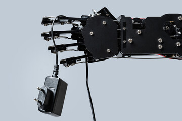 Real robotic hand with AC adapter. Concepts of AI takeover and Technological singularity
