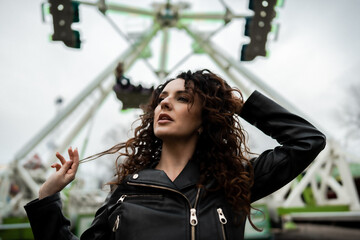 portrait of a young confident beautiful woman model in luna park posing playing with her dark curly...
