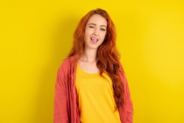 young beautiful red haired woman winking looking at the camera with sexy expression, cheerful and...