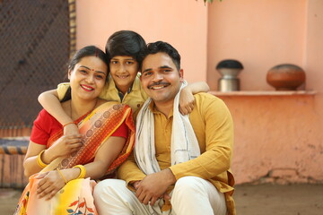 Indian happy farmer family in outdoors. husband wife and son enjoying happy moments of life. Rural India.