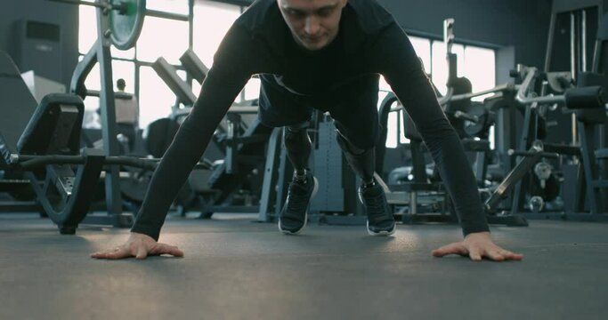 Confident disabled sportsman with prosthesis working out at sport center endurance, willpower Slow motion never give up, motivated gorgeous man doing press-up exercises at gym
