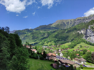 Lauterbrunnen valley, Jungfrau region, Switzerland. Mountain village, cottages, green summer Alps. View from the top. Swiss Alps. Hiking place. Blue sky, sunny day.