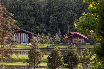 Fototapeta premium Modern wooden loft house for one family. Rent for privacy. An ideal place to relax. Wooden house by the water. Organic architecture. Minimalistic house with large panoramic windows for relaxation.