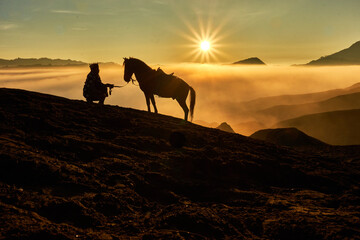 Fototapeta na wymiar Silhouette of a horse in hillsides surrounded by thick fog with and sun shines brightly
