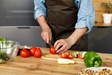 Midsection of a man cooking a salat from fresh vegetables in kitchen