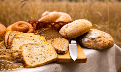 lot of different flavored bread, wheat, rye, on the table in the field outside