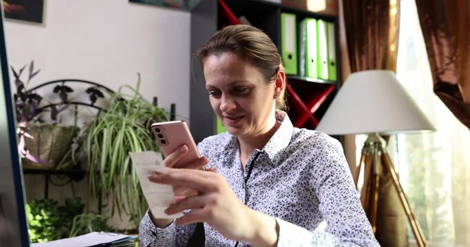 Smiling woman scanning two-dimensional code using mobile phone. Online payment via mobile app