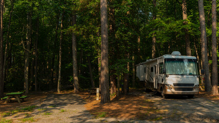 Rv motorhome parked at campsite with tall trees in forest - obrazy, fototapety, plakaty