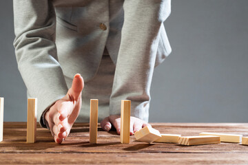 Businesswoman protecting dominoes from falling