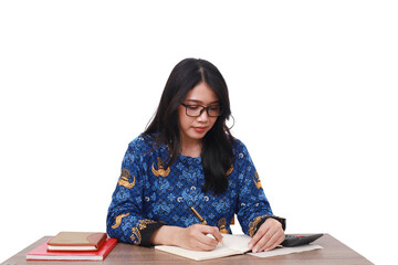 Asian female in batik korpri, indonesian traditional worker uniform writing something on a book