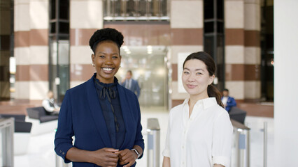 Portrait of two successful and ethnically diverse colleagues smiling to camera