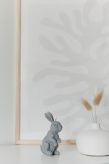 Creative composition of living room interior with copy space, stylish vase, wall with stucco.Home decor. Template. Hygge scene with candles on white background. Bunny candle. Bubbles candle