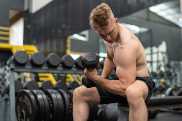 Fototapeta na wymiar Boxer athlete man in shirtless exercising with dumbbell weights at the gym. Male with fit muscular body training and workout fitness center.