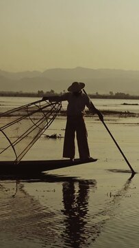 Myanmar travel attraction landmark - Traditional Burmese fishermen with fishing net at Inle lake in Myanmar famous for their distinctive one legged rowing style. Vertical video