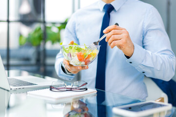 Unrecognizable businessman eating a vegetables salad for lunch, healthy and lifestyle concept.