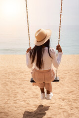 Vertical photo of a unrecognizable woman sitting in a swinger outdoors in the beach. Female...