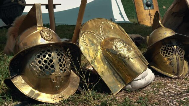 Gladiators helmets on the ground in military camp, golden helmets protecting gladiators from death on the battlefield, armour equipment of Roman gladiators
