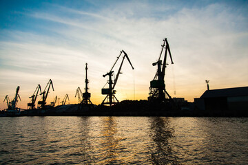 Silhouettes of cranes in the seaport at sunset.