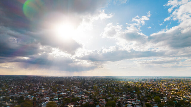 sky with sunbeams and clouds over the green city