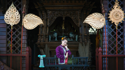 Pretty Asian woman wearing ancient native Thai traditional dress costumes sitting in the classic Thai house.