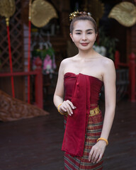 Pretty Asian women wearing ancient native Northern Thai traditional dress costumes posing standing in beautiful Thai houses.