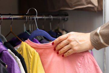 a woman takes a t-shirt out of the closet with clothes