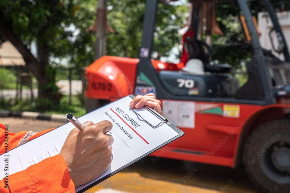 Wall mural a mechanical engineer is using heavy equipment checklist form for inspecting the factory forklift ve