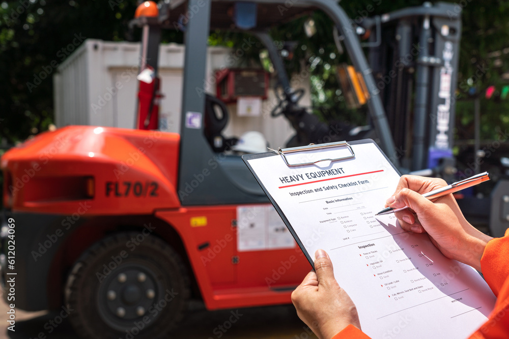 Wall mural a mechanical engineer is using heavy equipment checklist form for inspecting the factory forklift ve