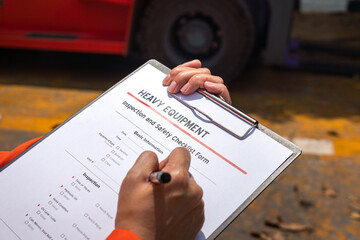 A mechanical engineer is using heavy equipment checklist form for inspecting the factory forklift...