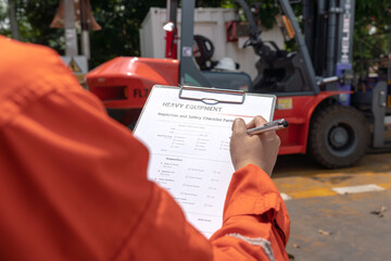 A mechanical engineer is using heavy equipment checklist form for inspecting the factory forklift...