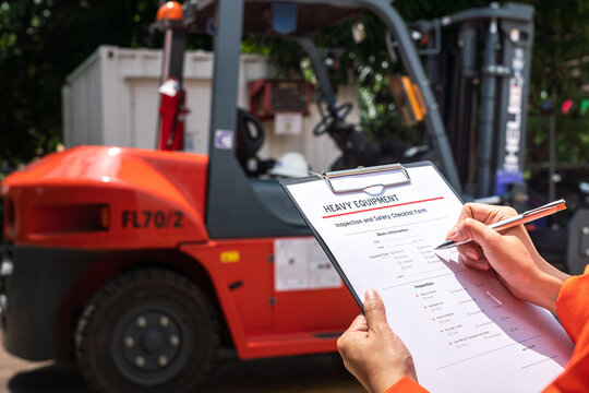 A Mechanical Engineer Is Using Heavy Equipment Checklist Form For Inspecting The Factory Forklift Vehicle (as Blurred Background). Industrial Working With Safety Practice Concept, Selective Focus. 