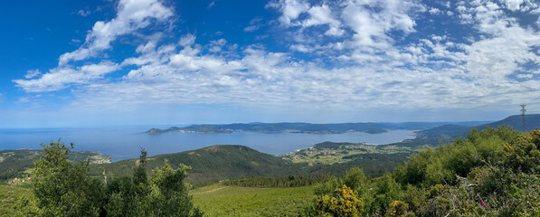 A stunning photo of Ria de Muros e Noia, Galicia, showcasing vast water, lush green hills, and...