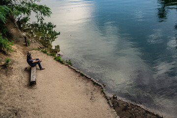 mężczyzna na ławce nad brzegiem jeziora, Szczecin, Jezioro Szmaragdowe, błękitna woda, relaks, spokój, medytacja, odbicie nieba - obrazy, fototapety, plakaty