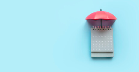 Umbrella over a calendar on a blue background.